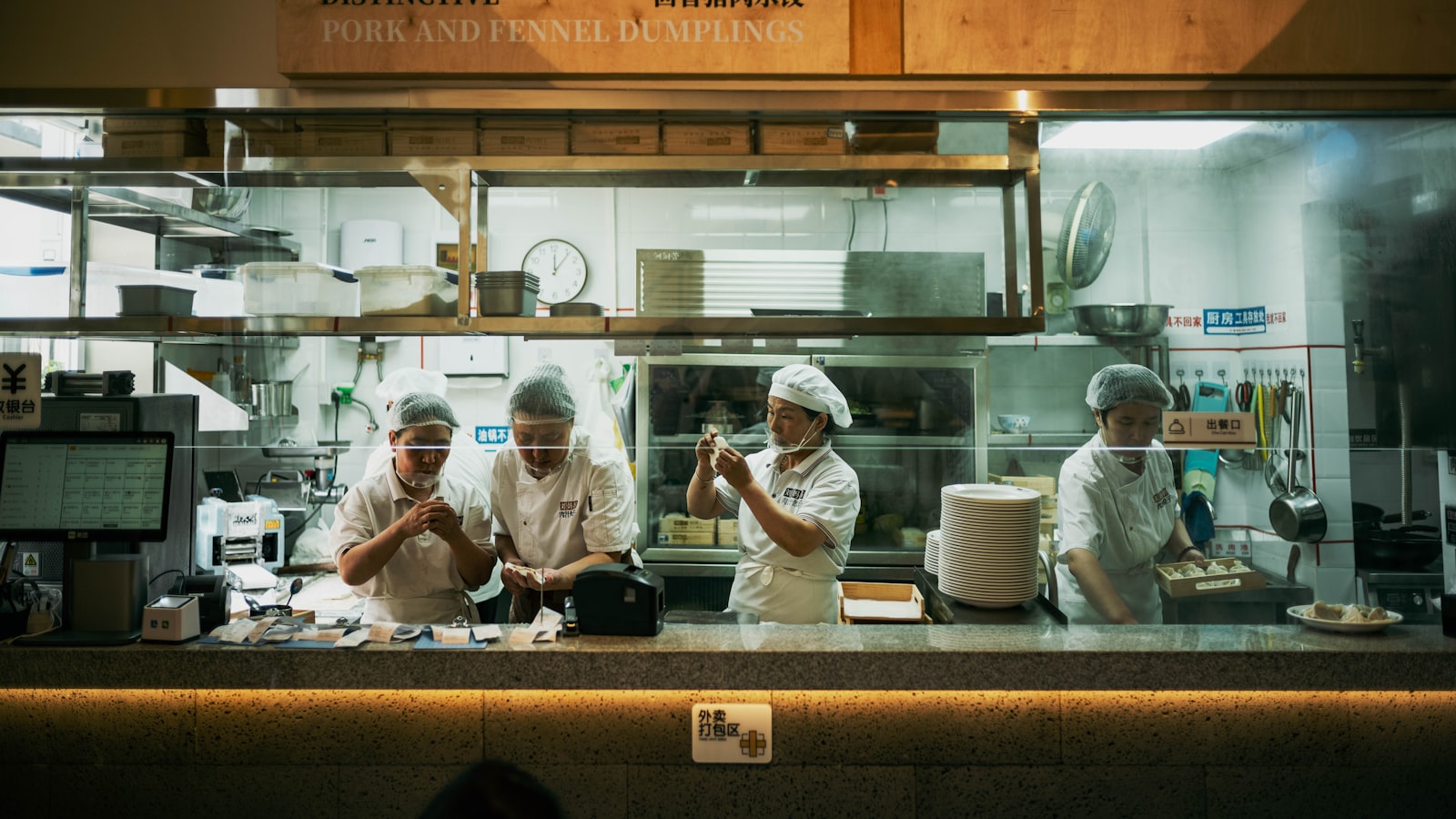 A restaurant crew working shoulder to shoulder behind the pass, the everyday version of restaurant team building